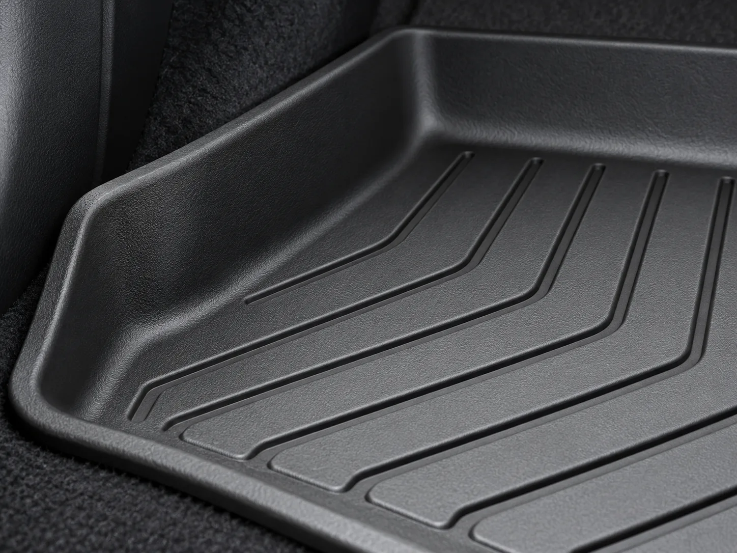 Close view of an illustrative raised edge and channels on a molded car floor liner