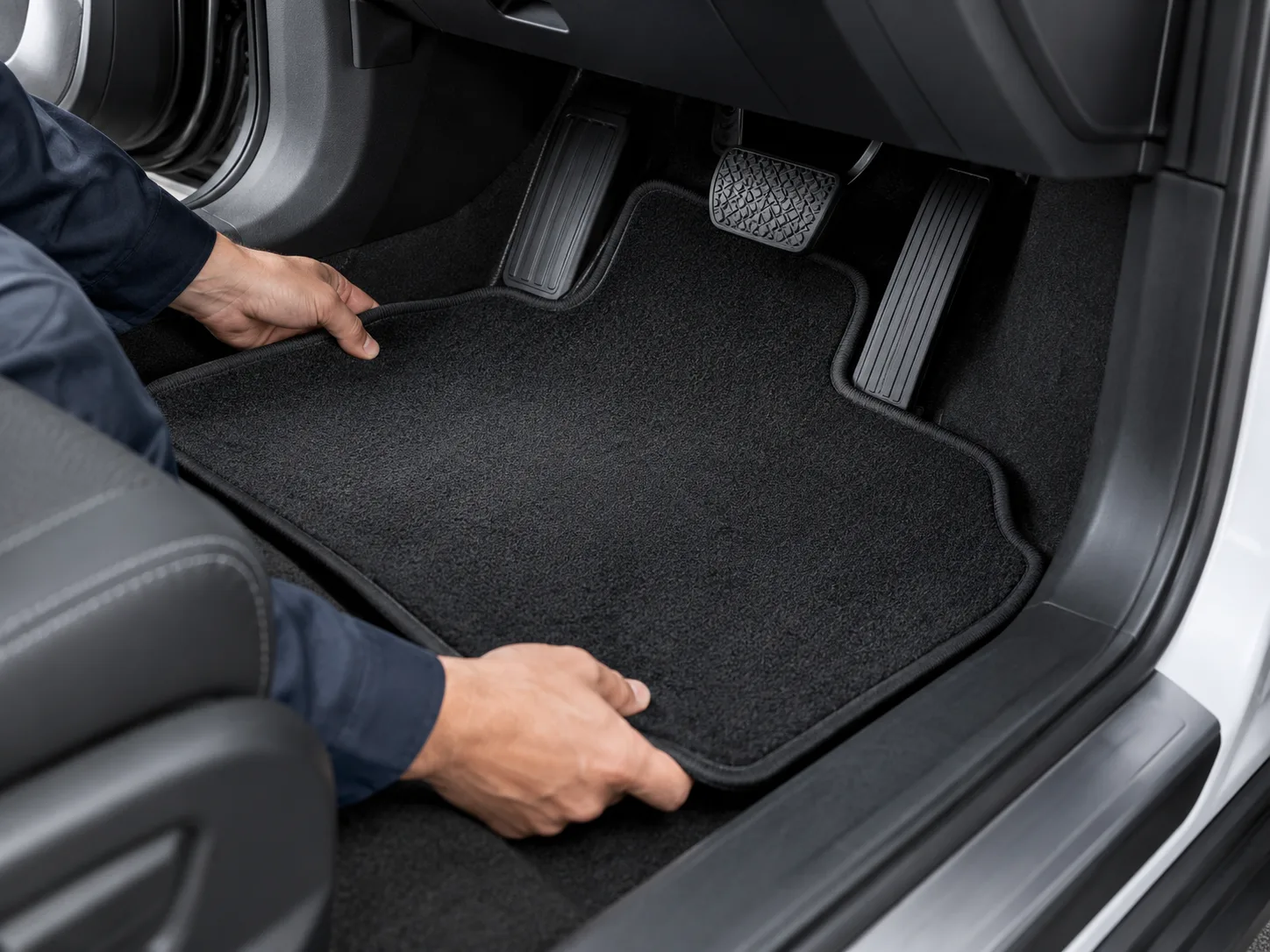 Illustrative floor-mat sample being checked against a vehicle footwell